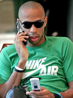 a man talking on a cell phone while wearing sunglasses and holding a smart phone to his ear