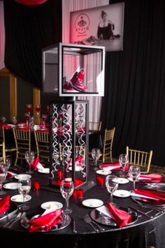 a black table with red napkins and silverware on it is set for an event