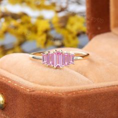 a pink tourmaline stone ring sitting on top of a velvet cushioned box