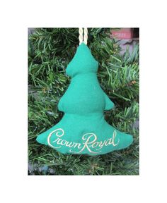 a green christmas tree ornament hanging from a pine tree with the words crown royal on it