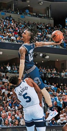 a basketball player jumping up to dunk the ball in front of another player with his head