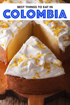 a cake with white frosting and orange sprinkles sitting on top of a wooden cutting board