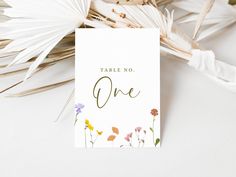 there is a card that says table no one on it with flowers and leaves around it