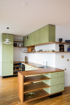 an empty kitchen with green cabinets and wooden flooring in front of the counter top