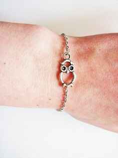 a close up of a person's arm wearing a bracelet with an owl on it