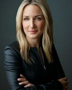 a woman with her arms crossed posing for a photo in front of a black background