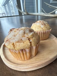 two muffins sitting on top of a wooden plate