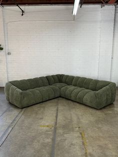 a large green sectional sofa sitting in a garage