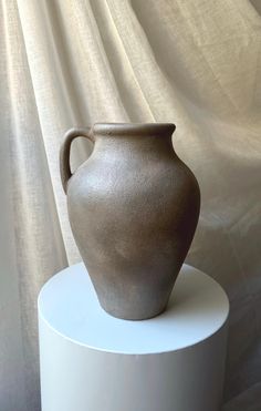 a brown vase sitting on top of a white pedestal