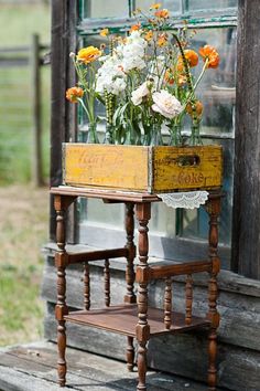 a wooden stand with flowers in it on the side of a building next to a window