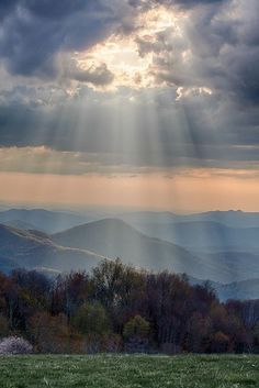 the sun shines through clouds over mountains and valleys in the blue ridge national park