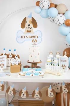 a dog themed birthday party with balloons, cake and desserts on a white table