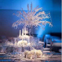 the centerpieces are decorated with flowers, candles and white frosted branches in glass vases