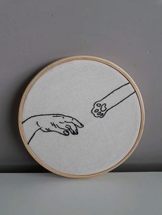 two hands are touching each other with one hand embroideryed onto the back of a hoop