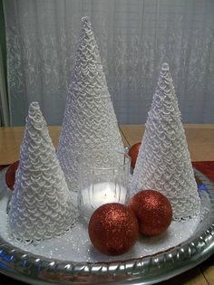 three plastic christmas trees sitting on top of a silver tray next to two red balls