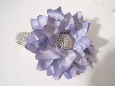 there is a purple flower that has been made from satin ribbon and brooches