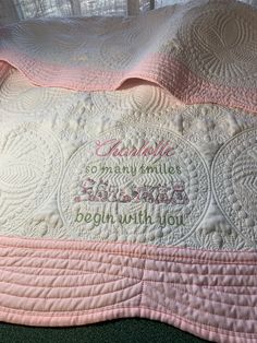 a pink and white quilted blanket with words written on the front in cursive writing