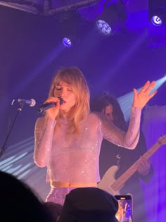 a woman singing into a microphone on stage