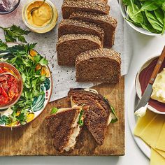 several slices of bread on a cutting board with salad and dips next to them