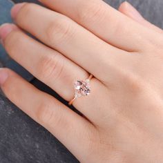 a woman's hand with a pink diamond ring on her left hand and the other hand holding an object in front of her