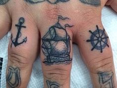 a person's hand with tattoos on it and an anchor, ship wheel and compass