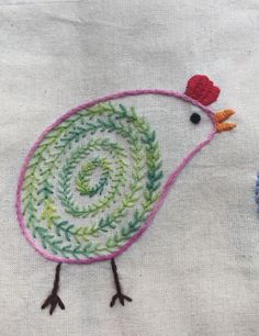 two small embroidered birds sitting next to each other on top of a white table cloth