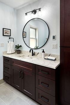 a bathroom with two sinks and a large round mirror