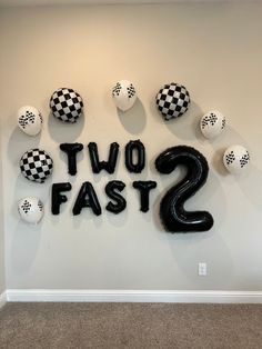 two fast 2 balloons are hanging on the wall in front of a sign with checkered balls