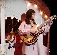 a woman is playing an electric guitar on stage