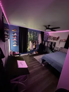 a bedroom with purple lighting and clothes on the wall