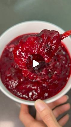 a person holding a spoon full of cranberry sauce