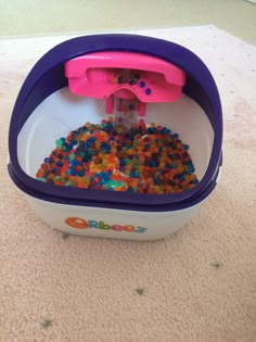 a bowl filled with lots of colorful beads sitting on top of a carpeted floor