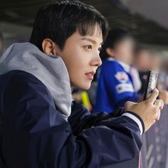 a young man holding a cell phone in his right hand and looking at the screen