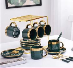 a table topped with green cups and saucers next to gold utensil holders