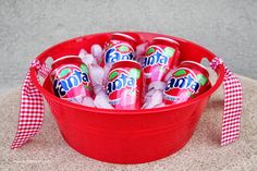 a red bucket filled with pink gummy bears sitting on top of a white and red checkered table cloth