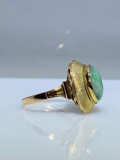 14K yellow gold ring with a natural jade. This vintage piece from the 70's is delicately made from the top of its scrolled shank to the textured bezel holding the stone in. The oblong oval Jade cabochon is a lovely green hue with white undertones. The basket is nice and opened eliminating any unnecessary weight. It measures 17mm x 12mm across the top and makes for the perfect statement ring. Finger size is 6.5 Feel free to message me if you have any other questions. Antique Gold Emerald Ring With Oval Cabochon, Antique Emerald Ring In Gold With Oval Cabochon, Oval Jade Rings In Yellow Gold, Elegant Oval Cabochon Emerald Collectible Ring, Formal Art Deco Oval Emerald Ring, Vintage Oval Jade Rings, Vintage Oval Jade Emerald Ring, Art Deco Oval Cabochon Rings, Vintage 14k Gold Oval Cabochon Emerald Ring