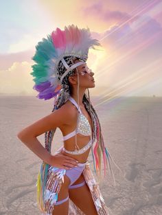 a woman in a colorful headdress standing on the beach with her hands on her hips