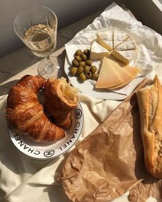 bread, cheese and olives are sitting on a table next to some wine glasses