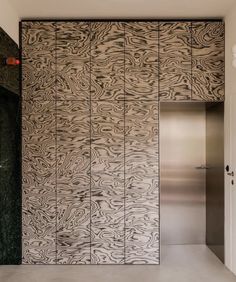 an elevator in a modern building with wood panels on the wall and metal doors that lead to another room