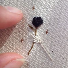 someone is stitching a black flower on a white piece of cloth