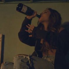 a woman drinking from a wine bottle while sitting down