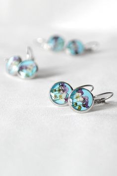 Sky blue earrings with tiny purple flowers for girls or womens. Real flower is carefully protected with clear resin and stay beautiful for a long time. This delicate piece of nature will be a nice wedding gift for bridesmaids and flower girl, for Mother's Day or any other occasion. Diameter of earrings: 10 mm, 12 mm and 14 mm (0.40'', 0.45'' and 0.55 inches). here you can find other my earrings and stud earrings: ☘ https://etsy.me/2PJWIB0 ☘ https://etsy.me/2PlRTPd Also you can choose jewelry in Sky Blue Earrings, Light Blue Earrings, Real Flower Earrings, Valentine Gifts Jewelry, Pressed Flower Earrings, Plant Jewelry, Romantic Gifts For Her, Real Flower Jewelry, Spring Earrings