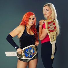 two beautiful women standing next to each other holding wwe belts and posing for the camera