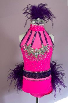 a mannequin with purple feathers and jewels on it's neck, in front of a gray background