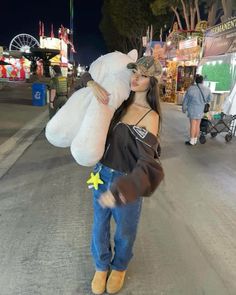 a woman is walking down the street with a large stuffed animal in her hand and she is holding a teddy bear