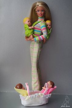 a barbie doll holding two dolls in her arms