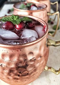 three copper mugs filled with ice and cherries