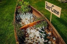 a wooden boat filled with beer bottles on top of a lush green field next to a sign that says deer dance