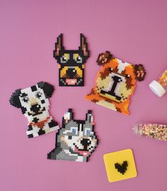 four pieces of bead art on a purple surface with beads and glues to make them look like dogs