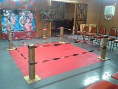 an indoor wrestling ring is set up with red and black tape on the floor, surrounded by chairs